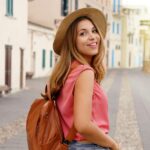 Young stylish tourist woman walking down a Spanish city street while looking back at the camera and smiling