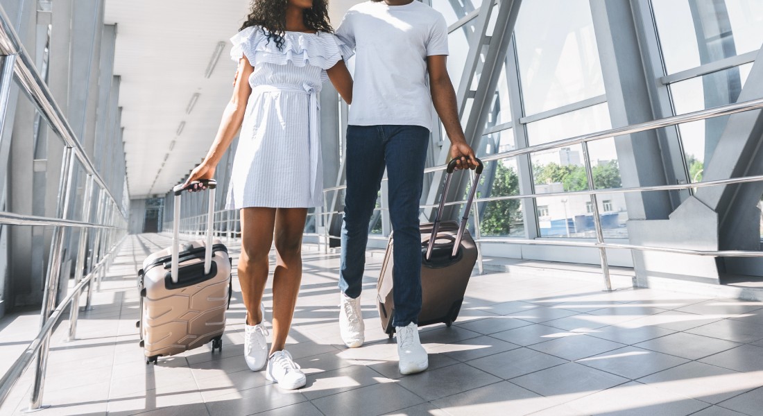 A couple walking through their terminal at an airport in sneakers and easy-to-wear travel outfits.