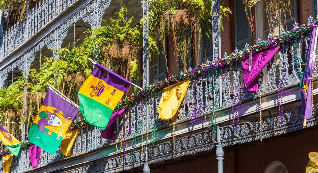 A building in the French Quarter of New Orleans decorated with colorful beads, flags, and banners to celebrate Mardi Gras.