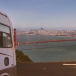 An RV parked at a viewpoint that is overlooking the Golden Gate Bridge in San Francisco on a sunny day.