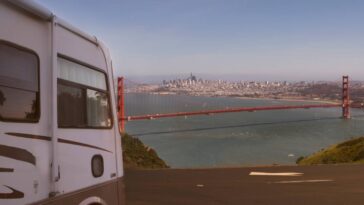 An RV parked at a viewpoint that is overlooking the Golden Gate Bridge in San Francisco on a sunny day.